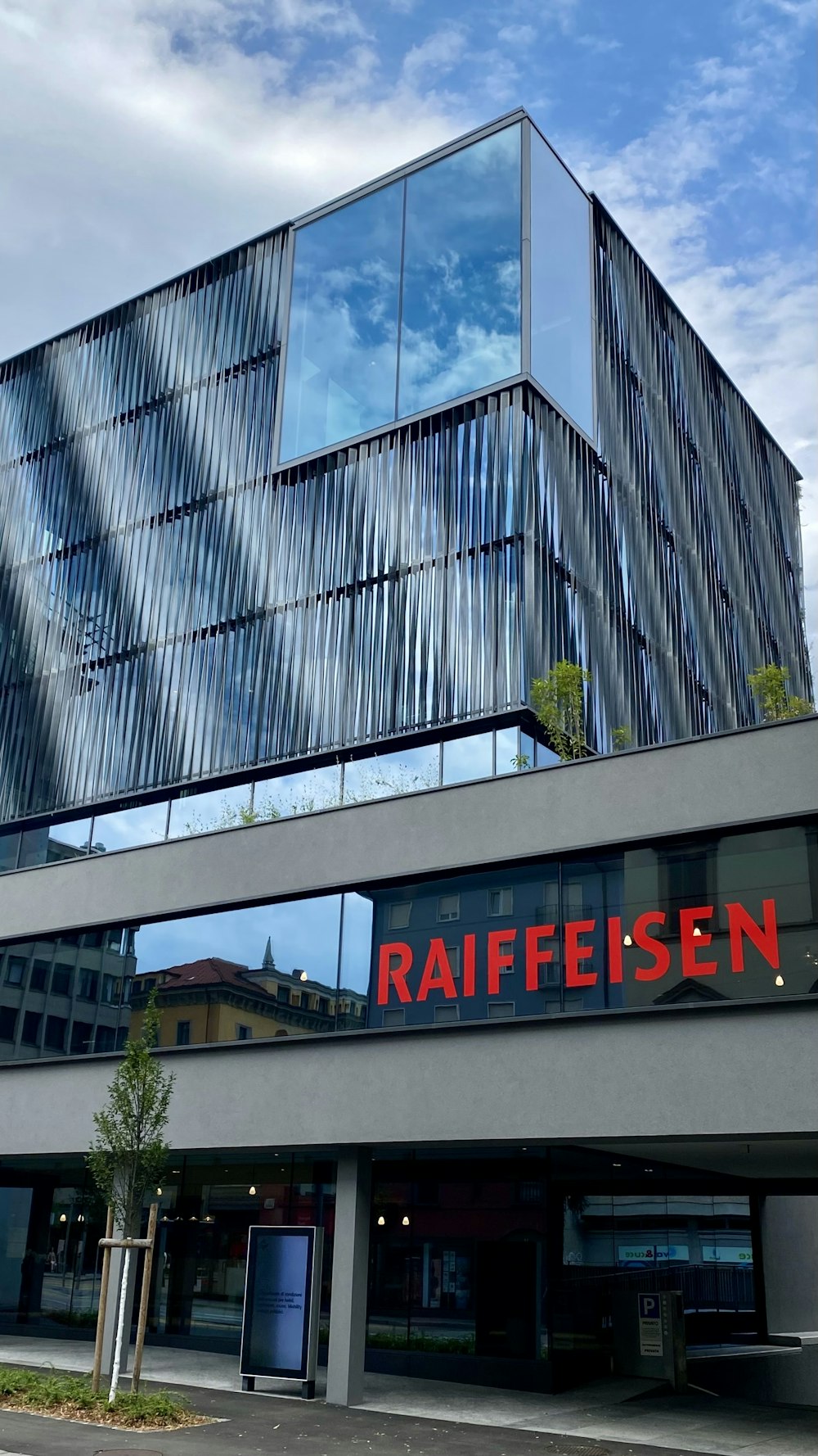 Un edificio con una fachada de cristal y un letrero rojo