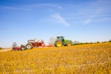 Modern agricultural implement attached to a tractor moving through green farmland