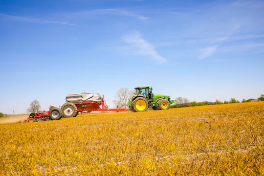 Heavy-duty tractor lift arms lifting a large farming implement in a field