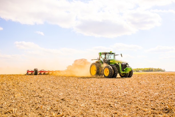 A tractor preparing a fertile field under a bright blue sky.