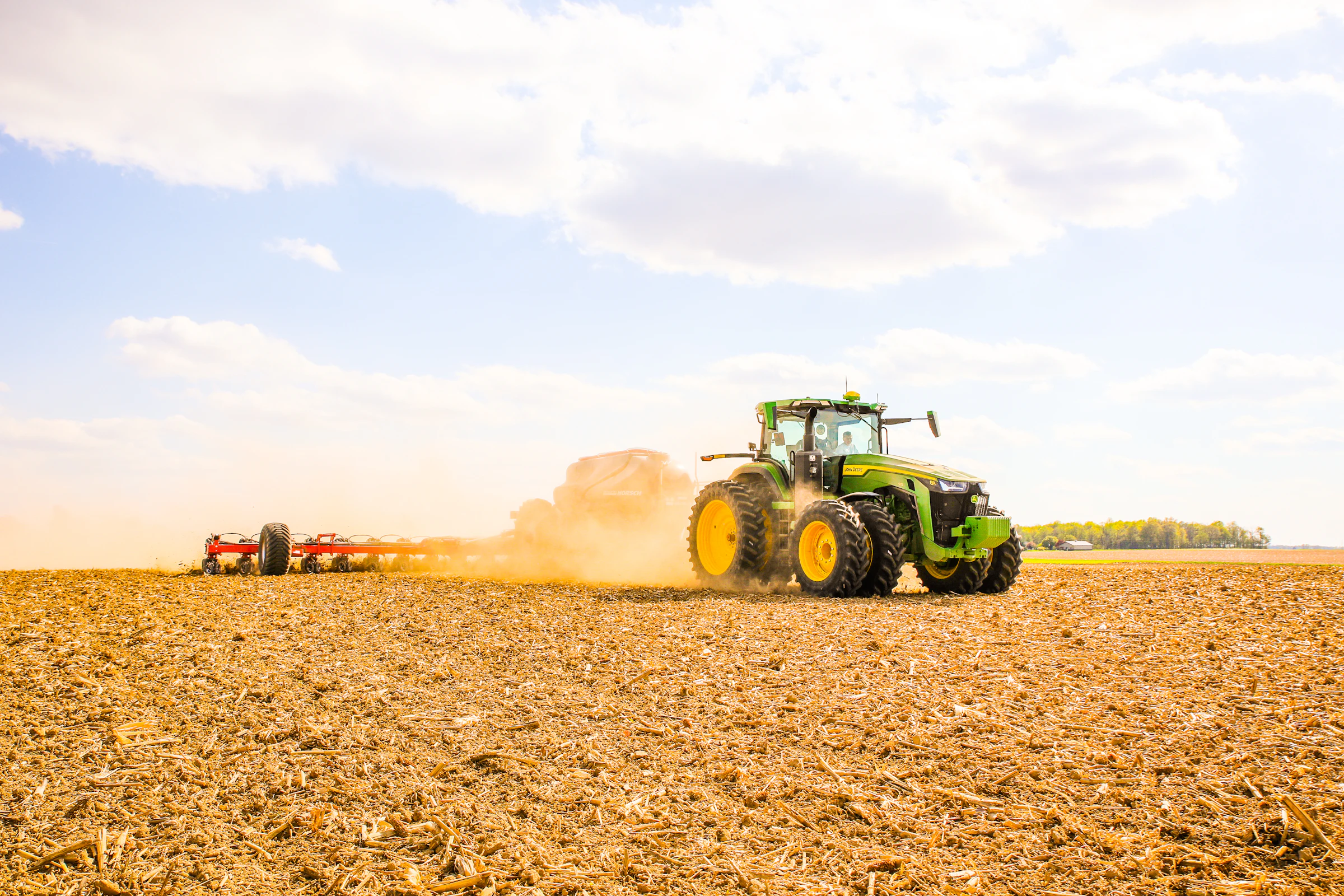 A tractor plowing a field with a trailer