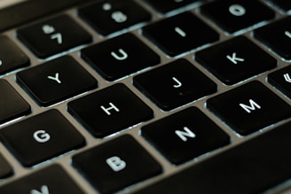 A close-up of hands typing on a laptop with digital game keys displayed on the screen.