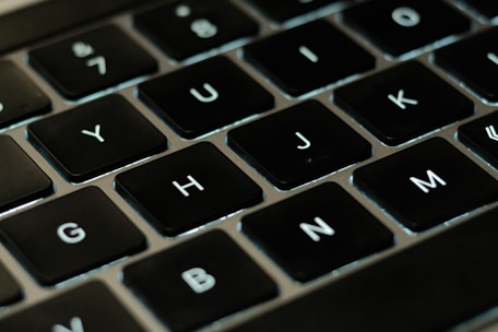 A close-up of hands typing on a laptop with digital game keys displayed on the screen.