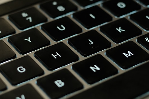 A close-up of a person typing on a laptop with acronyms displayed on the screen.