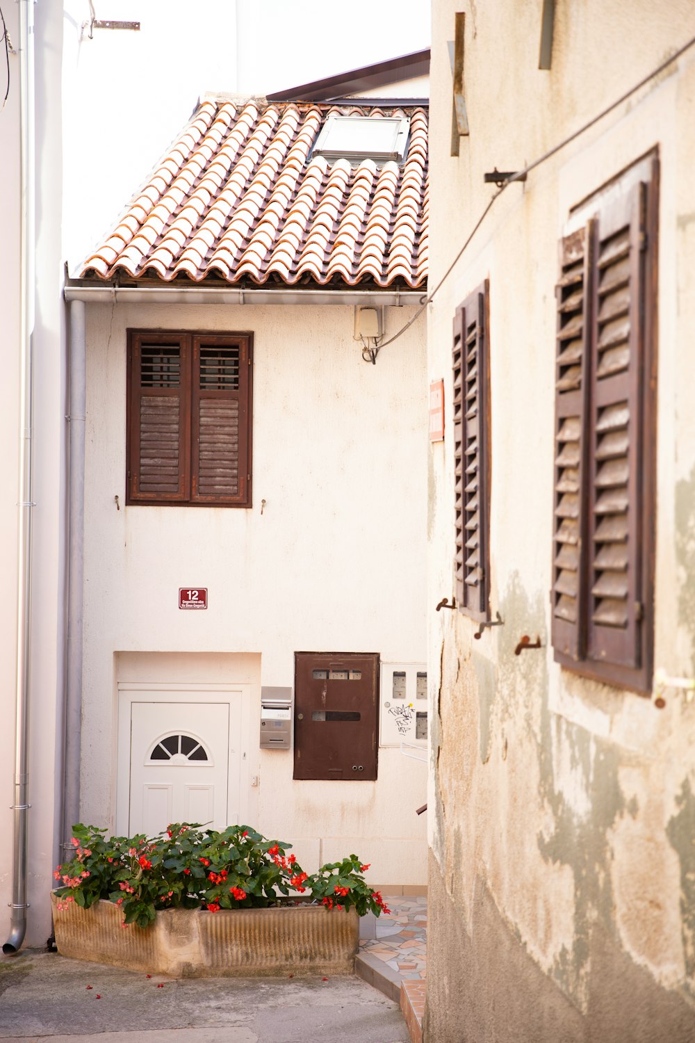 a white building with brown shutters and a flower box