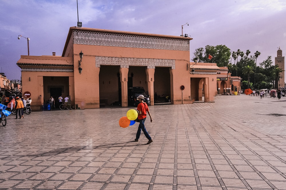 a man walking across a street holding a kite