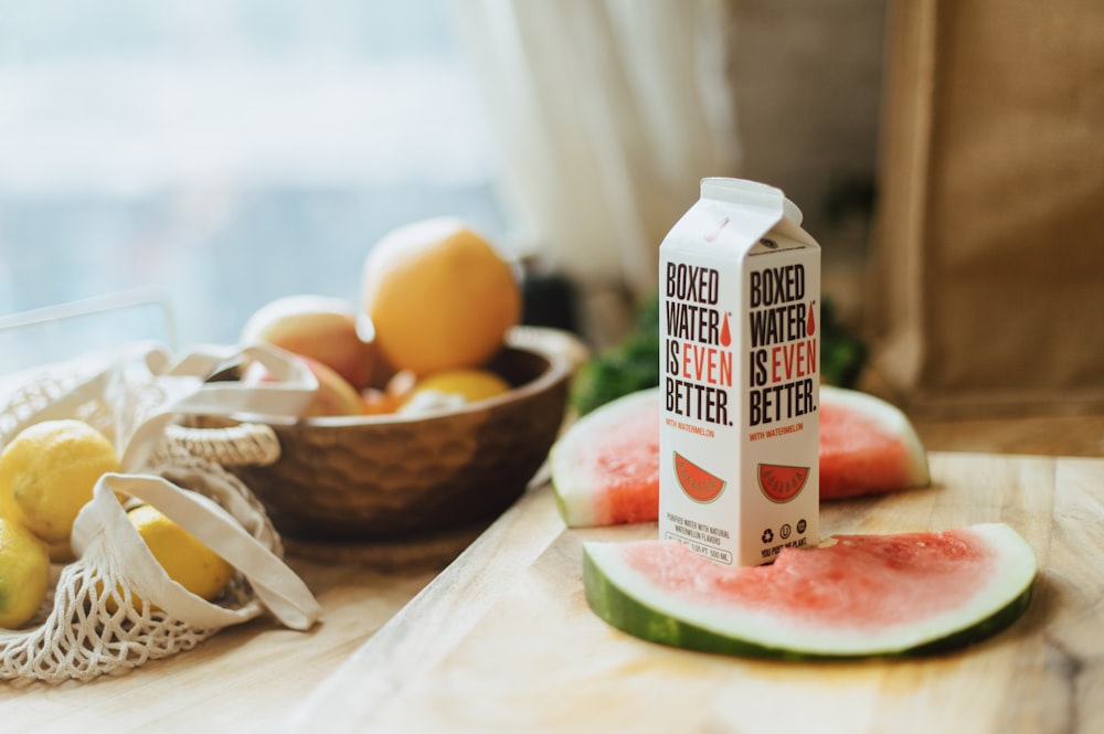 a bottle of watermelon water sitting on top of a wooden cutting board