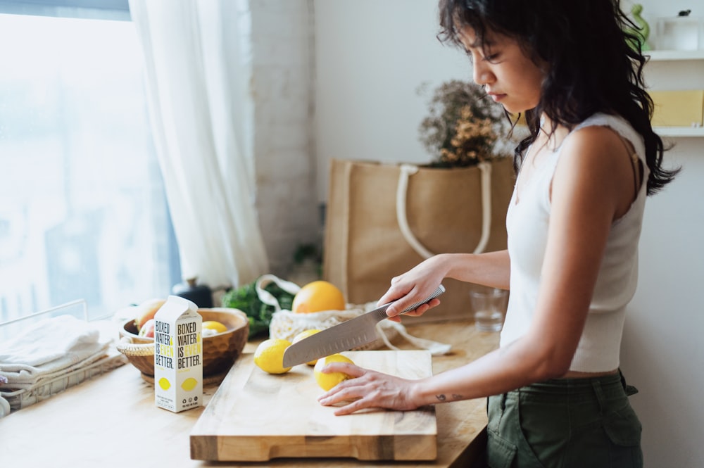 a woman cutting lemons on a cutting board