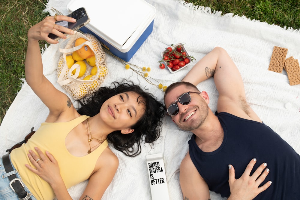 a man and a woman laying on a blanket on the grass