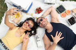 a man and a woman laying on a blanket with fruit
