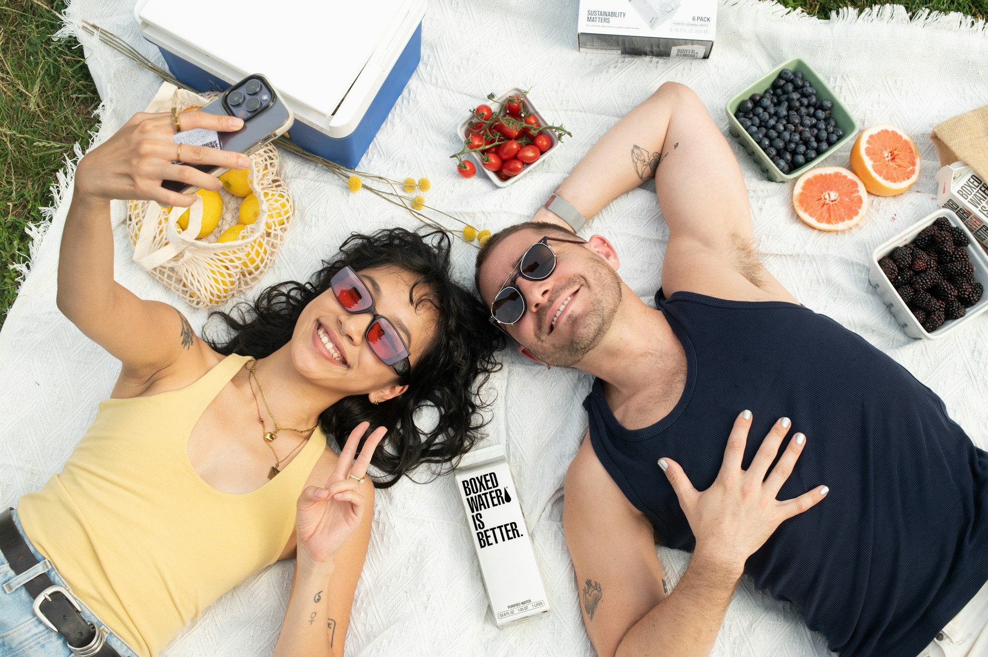 a man and a woman laying on a blanket with fruit