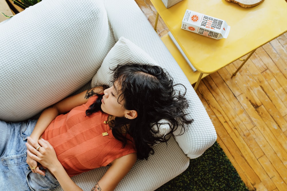 a little girl laying on a white couch