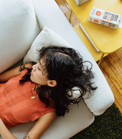 a little girl laying on a white couch