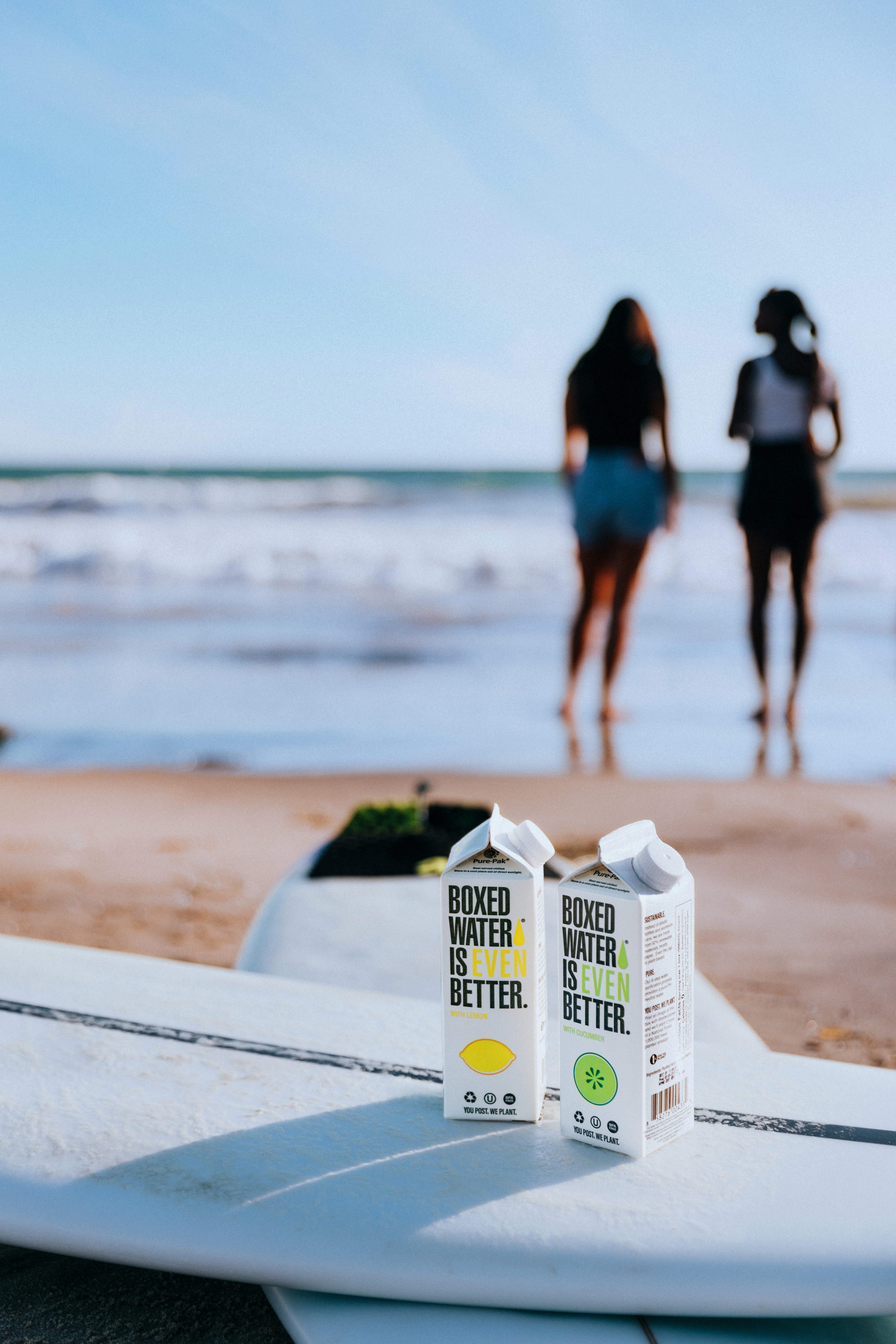 a couple of people walking on a beach next to a surfboard