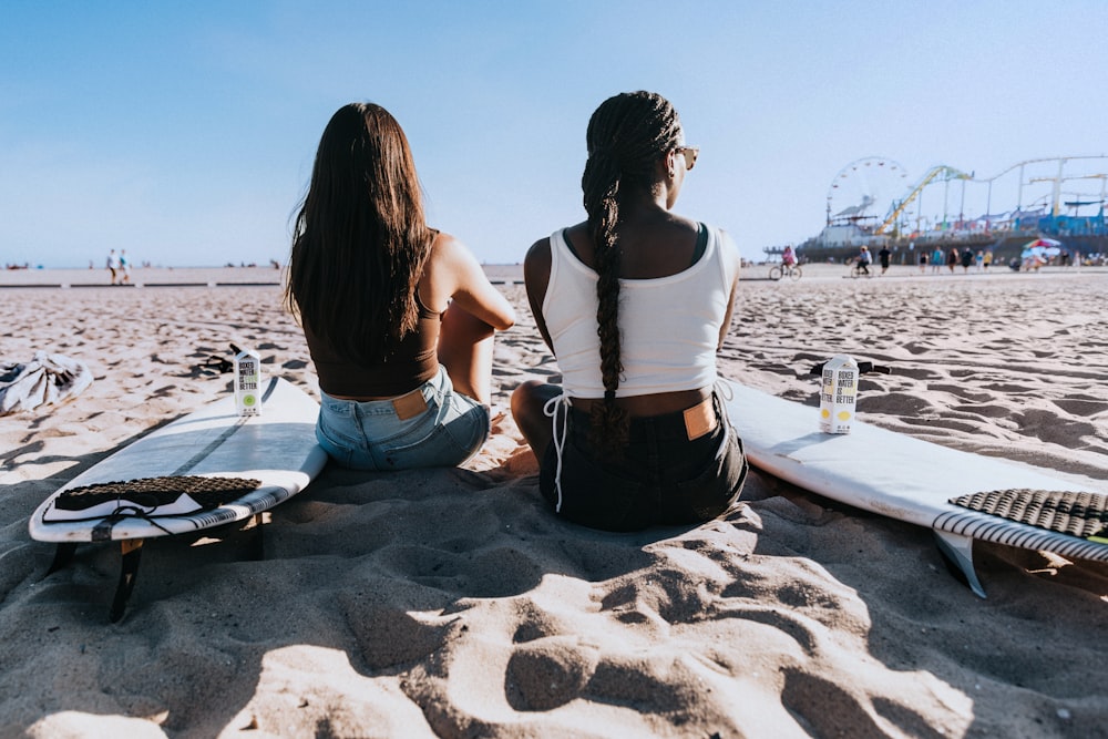 um casal de mulheres sentadas em cima de uma praia de areia