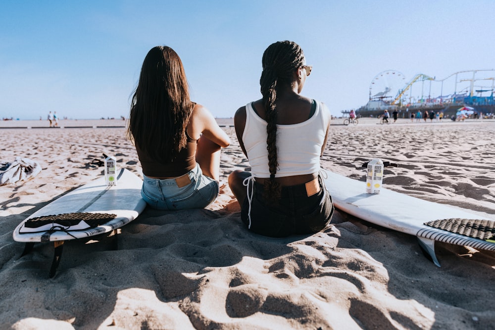 a couple of women sitting on top of a sandy beach