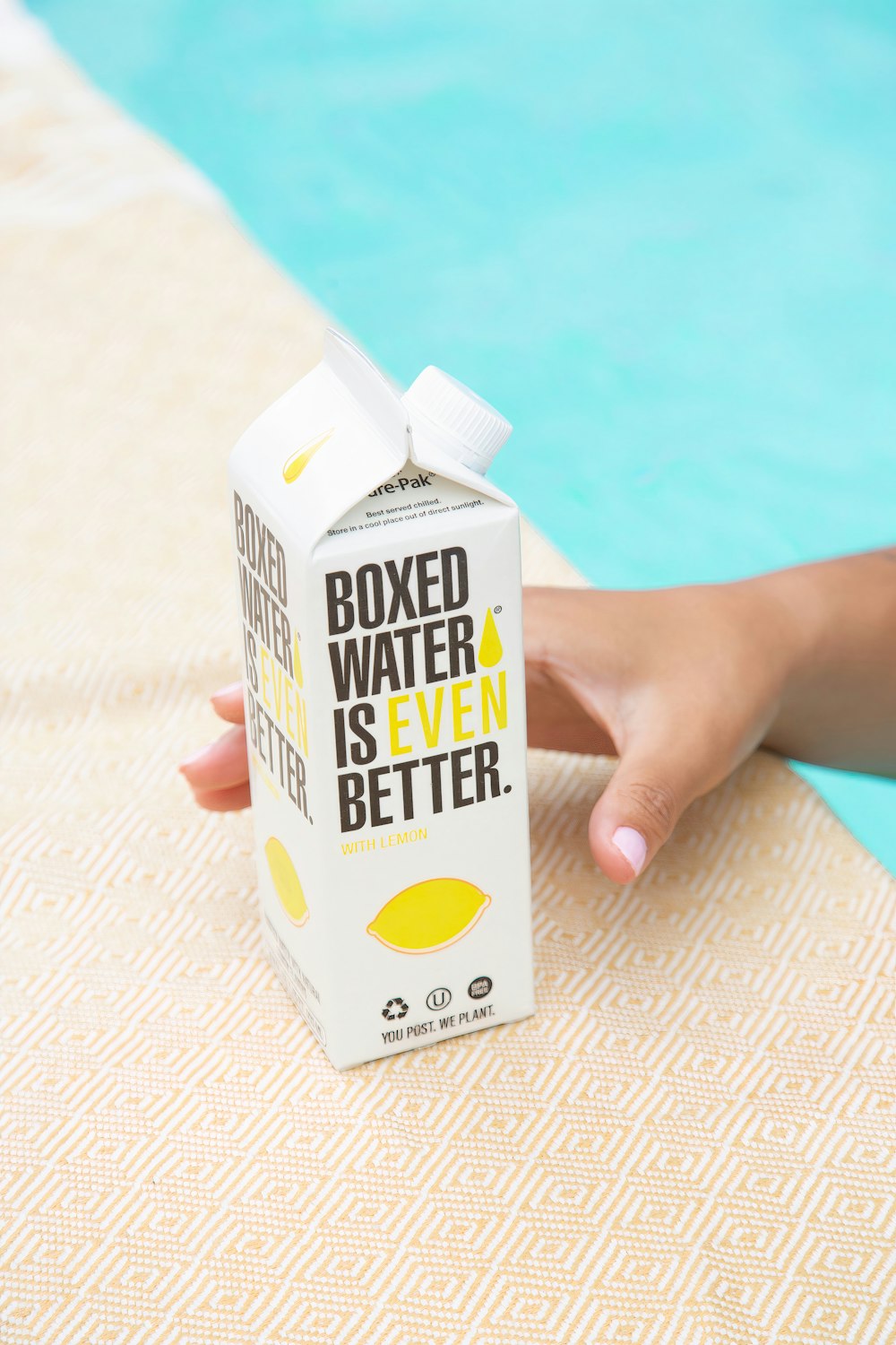 a person holding a carton of water next to a swimming pool