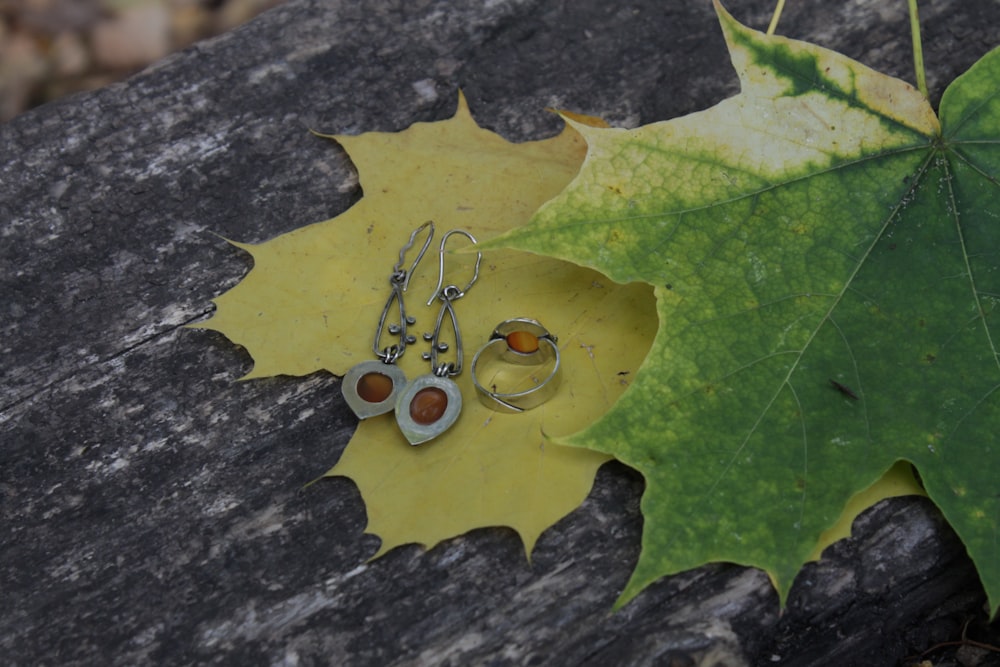 a pair of earrings sitting on top of a leaf