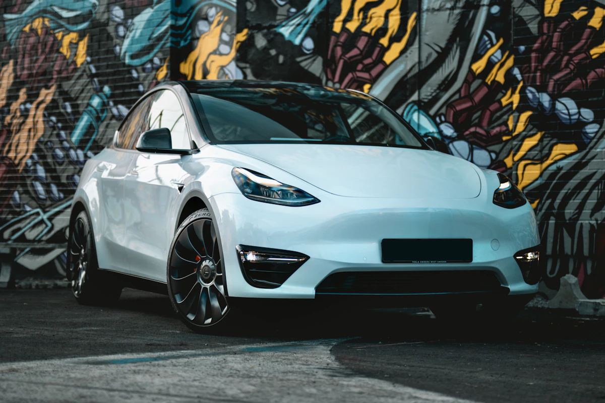 A white Tesla Model Y against a brightly painted wall