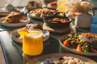 a table topped with plates of food and a glass of orange juice