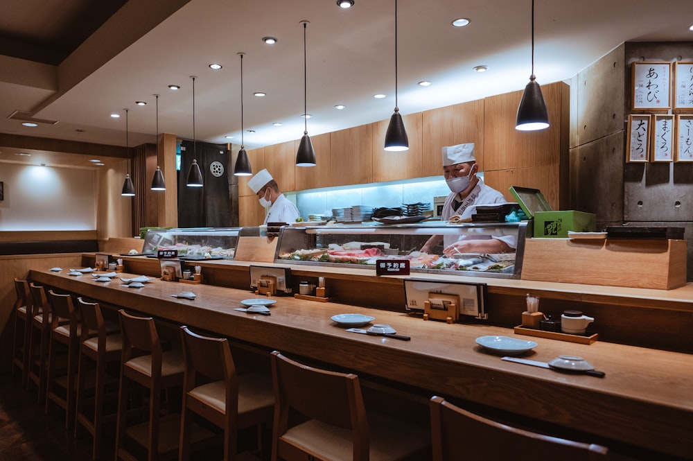 a restaurant with a long counter and a chef behind the counter