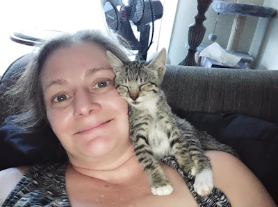 A smiling pet owner holding a content cat after a veterinary check-up.