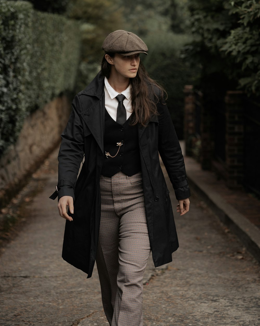 a woman walking down a street wearing a hat and coat