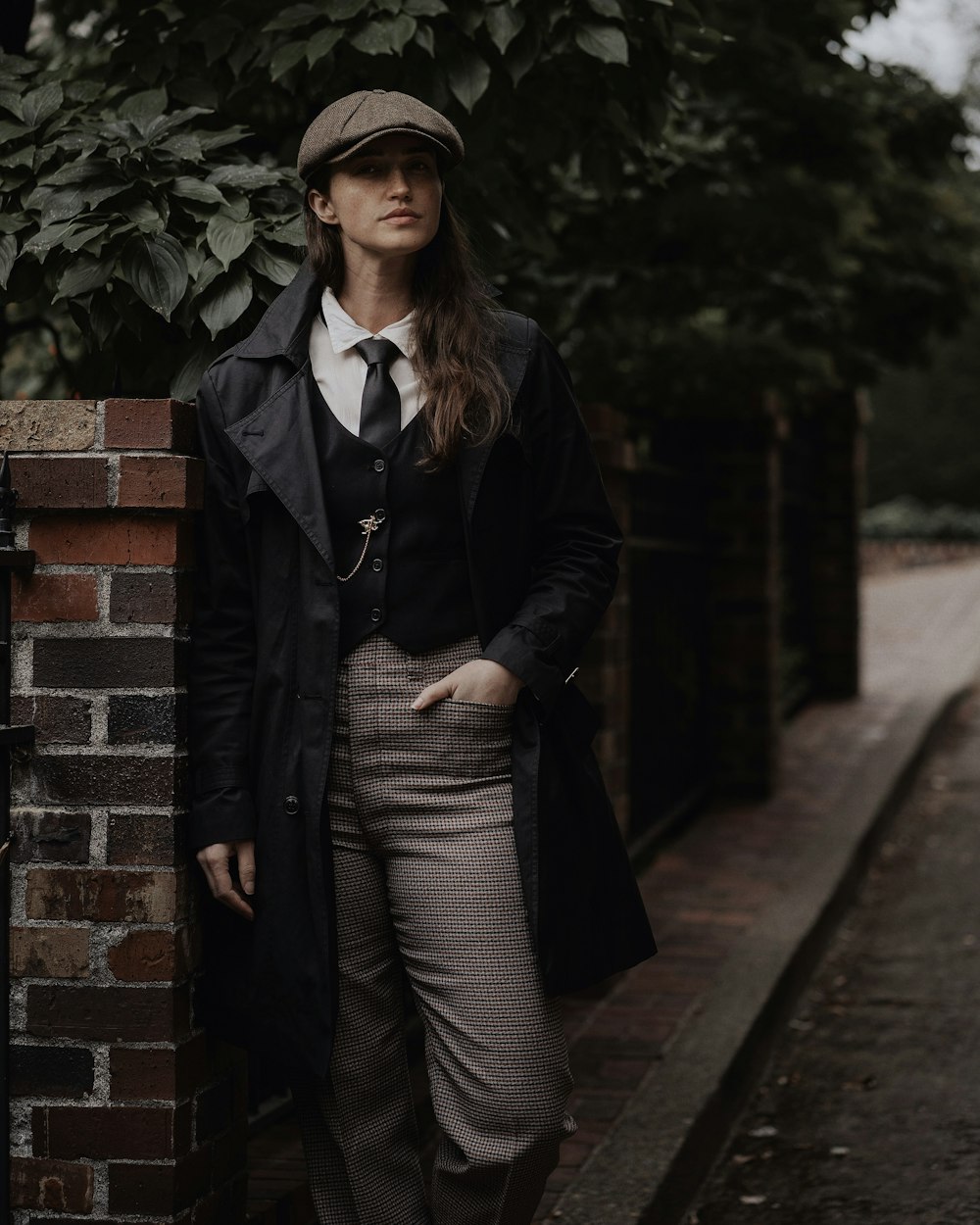 a woman standing next to a brick wall