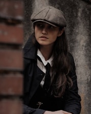 A stylish flat cap displayed against a brick wall backdrop in London.