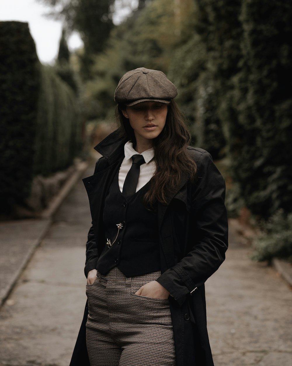 a woman standing on a sidewalk wearing a coat and tie