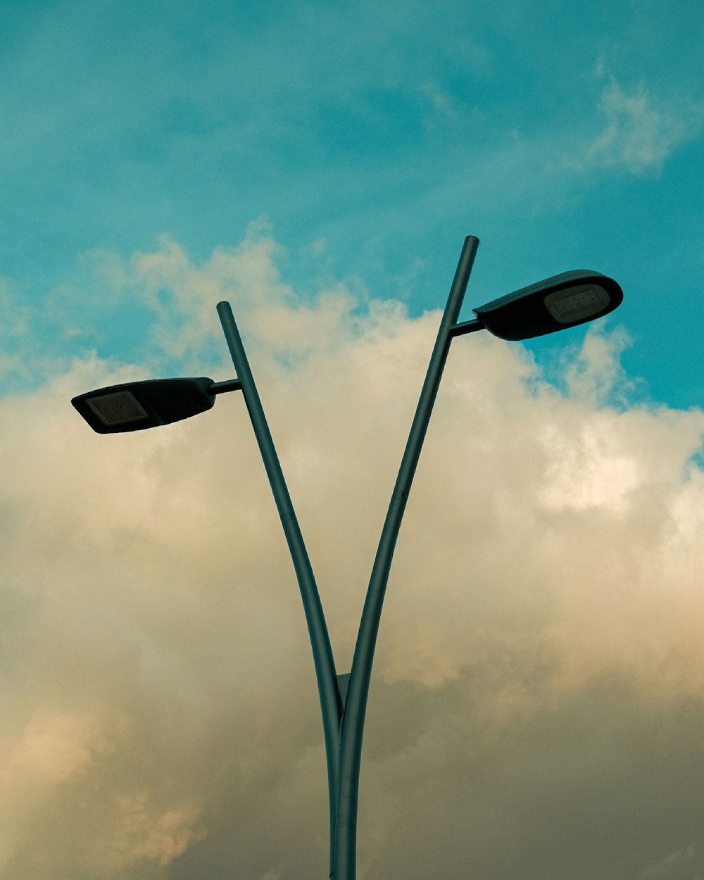 a couple of street lights sitting under a cloudy sky