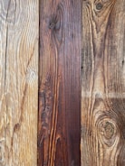 Natural wood planks with distinct grain patterns, showing variations in color from light tan to deep brown.