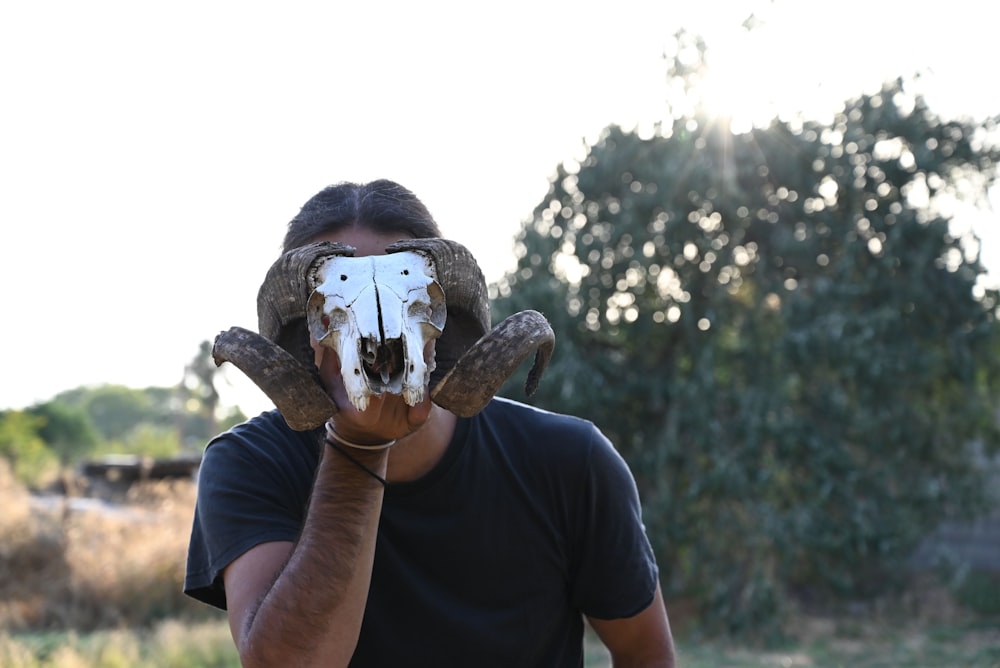 a man holding a cow skull in front of his face