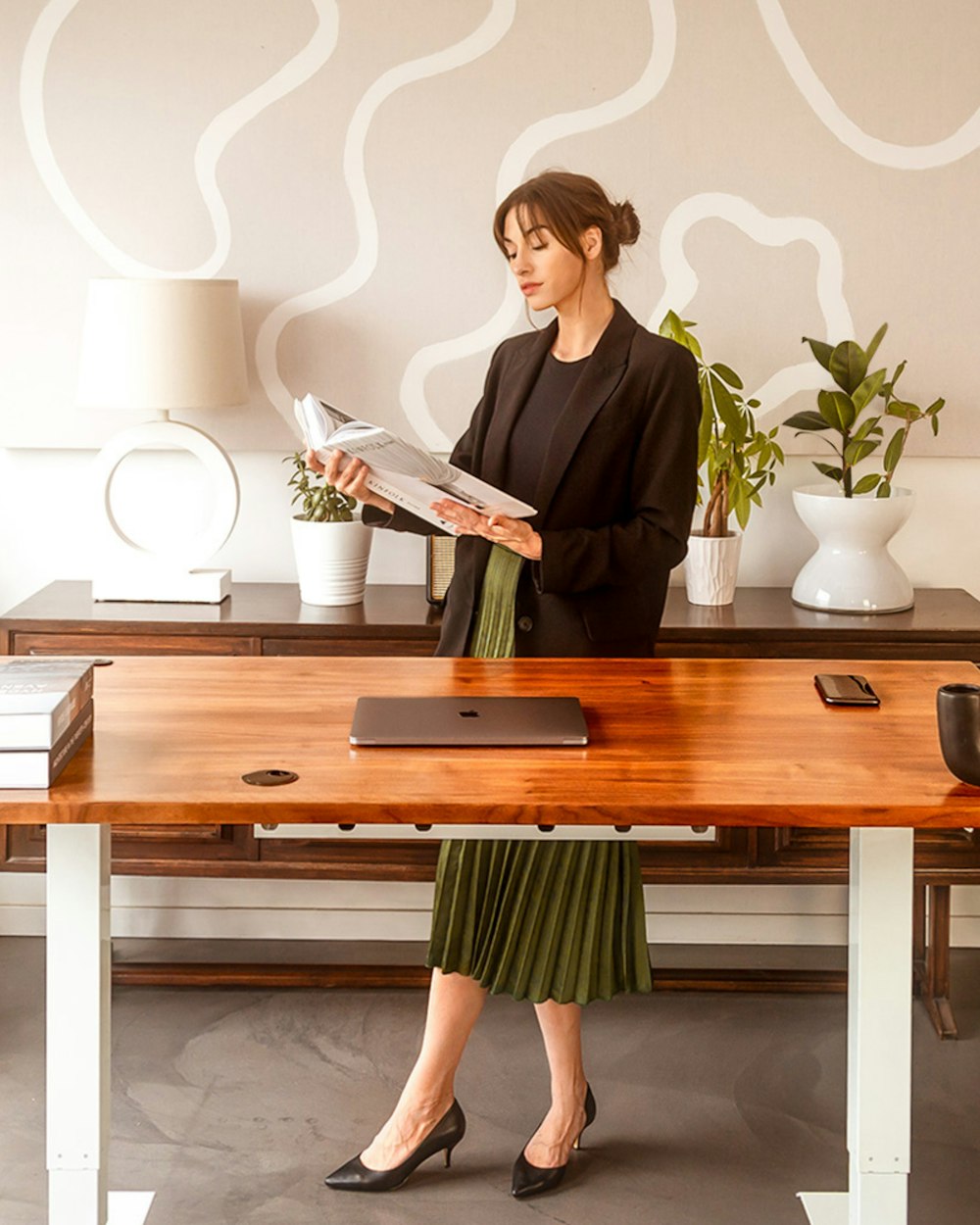 a woman sitting at a desk reading a magazine