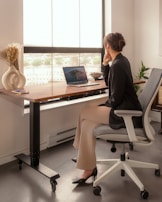 A side view of a person sitting with perfect posture using a sit-stand desk.