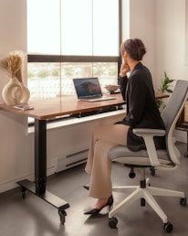 A cozy workspace featuring a sleek desk and ergonomic chair near a large window.