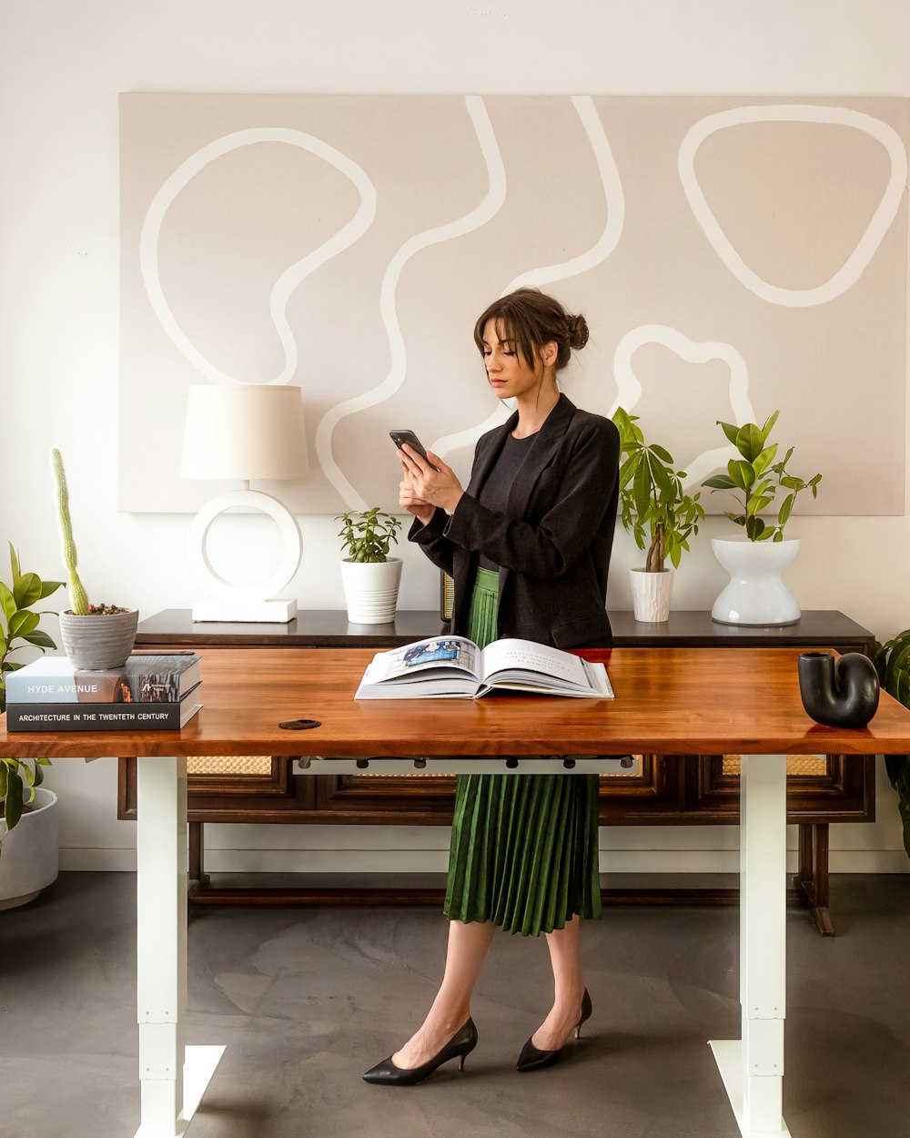 a woman standing in front of a desk holding a cell phone