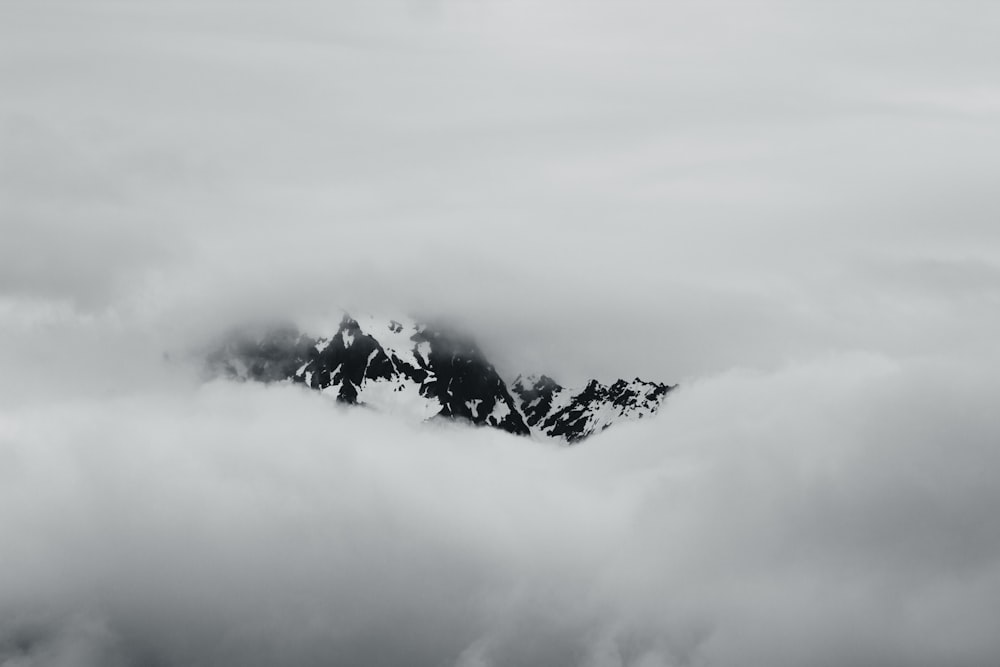 a black and white photo of a mountain covered in clouds