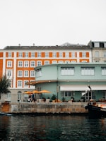 Cozy hotel facade overlooking the waterfront with people enjoying outdoor seating.