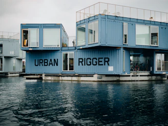 a group of blue shipping containers sitting on top of a body of water