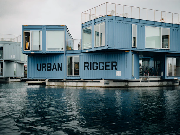 a group of blue shipping containers sitting on top of a body of water