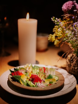 A vibrant bowl of fresh, colorful salad topped with edible flowers and a drizzle of dressing, set on a rustic wooden table.