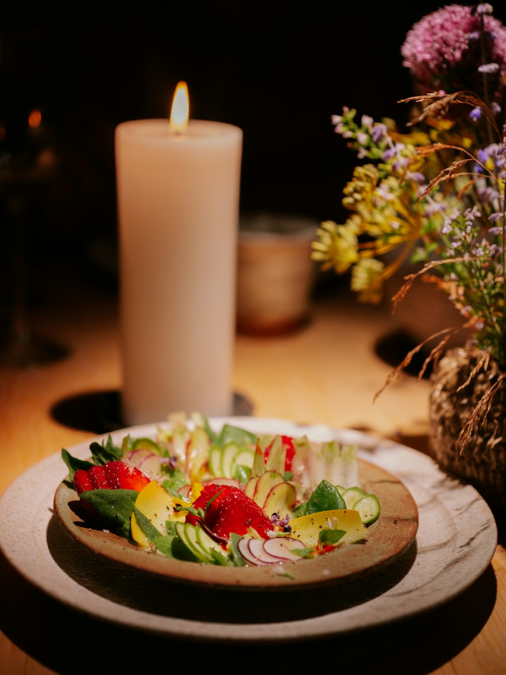 a plate of food on a table next to a candle