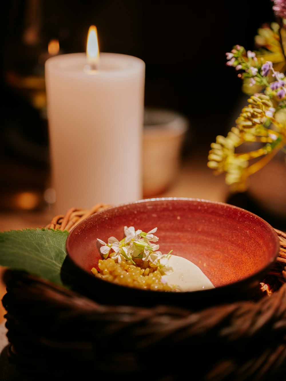 a bowl of food with a candle in the background