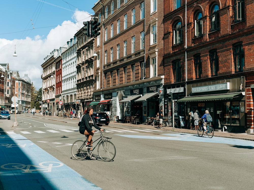 a man riding a bike down a street next to tall buildings