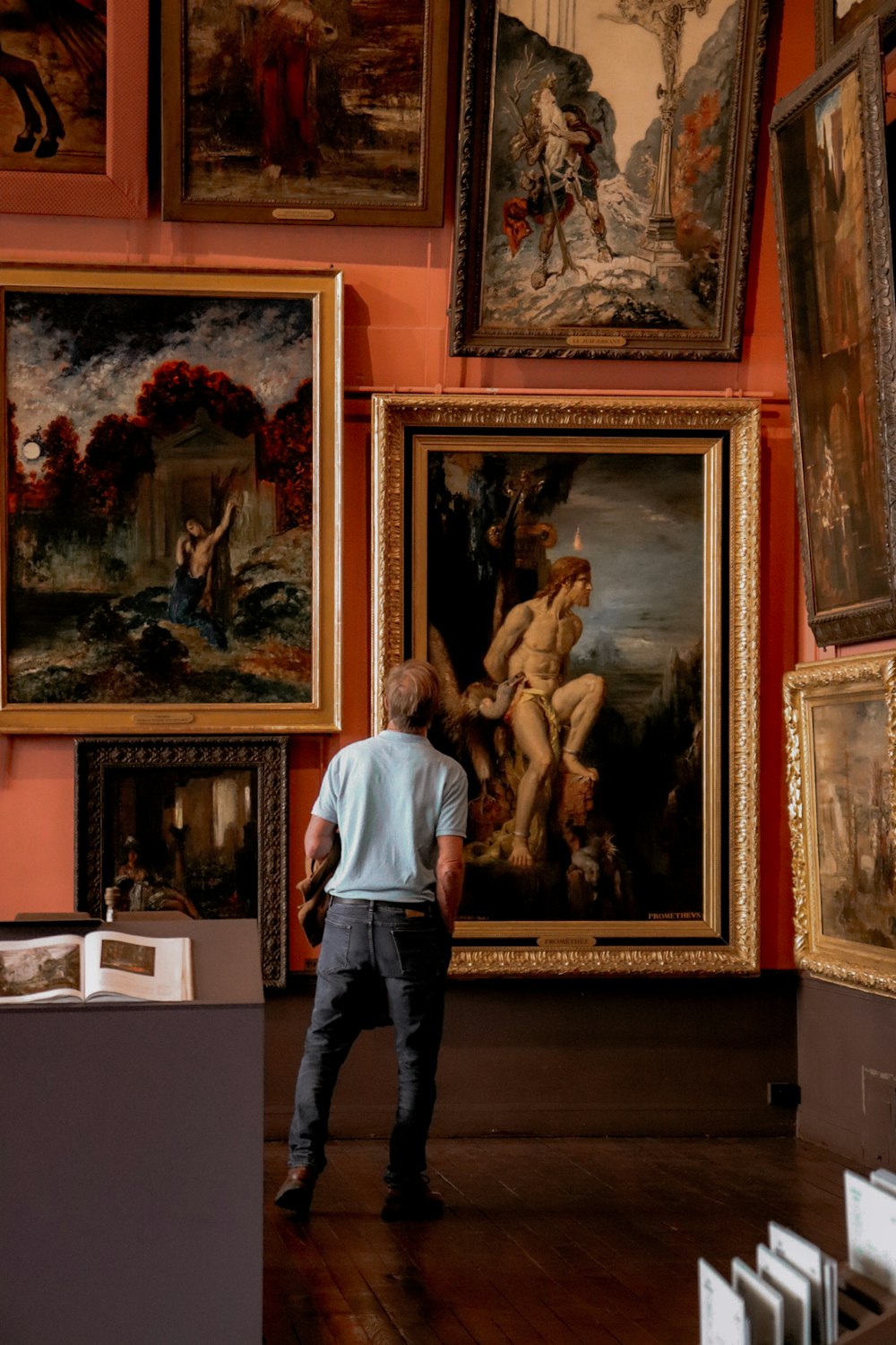 a man standing in front of a bunch of paintings