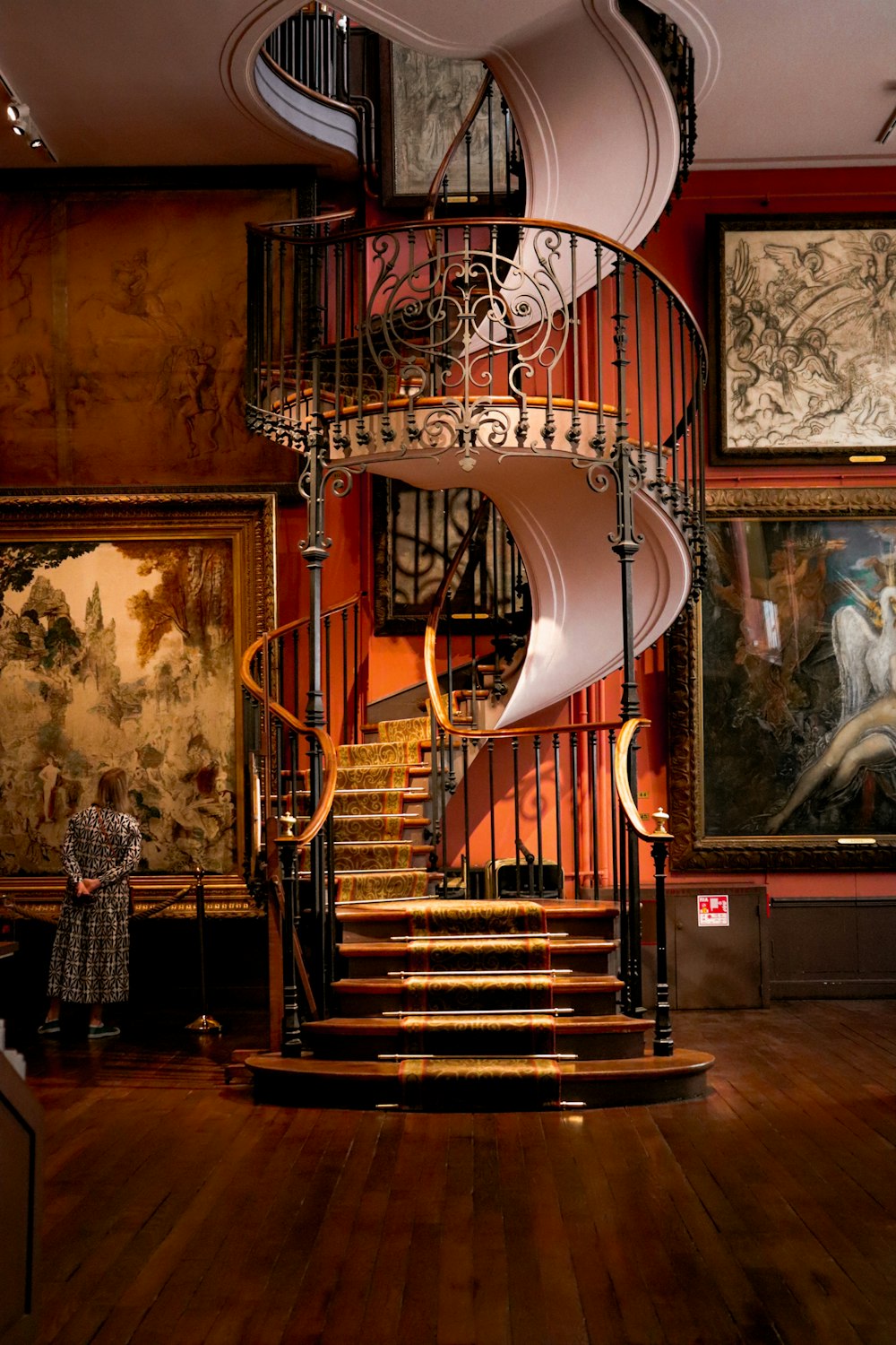 a spiral staircase in a museum with paintings on the wall