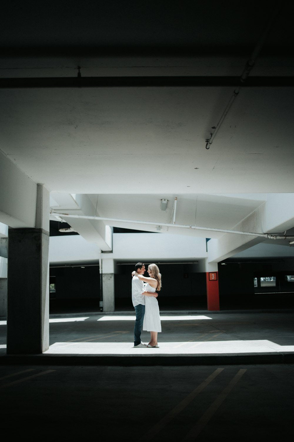 a man and woman standing in an empty parking garage