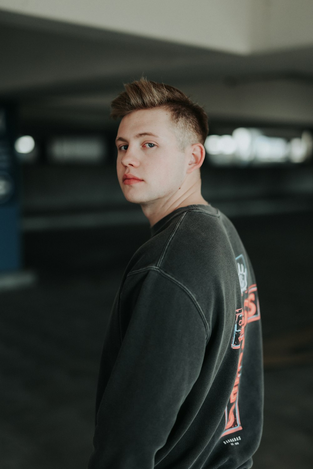 a young man standing in a parking garage