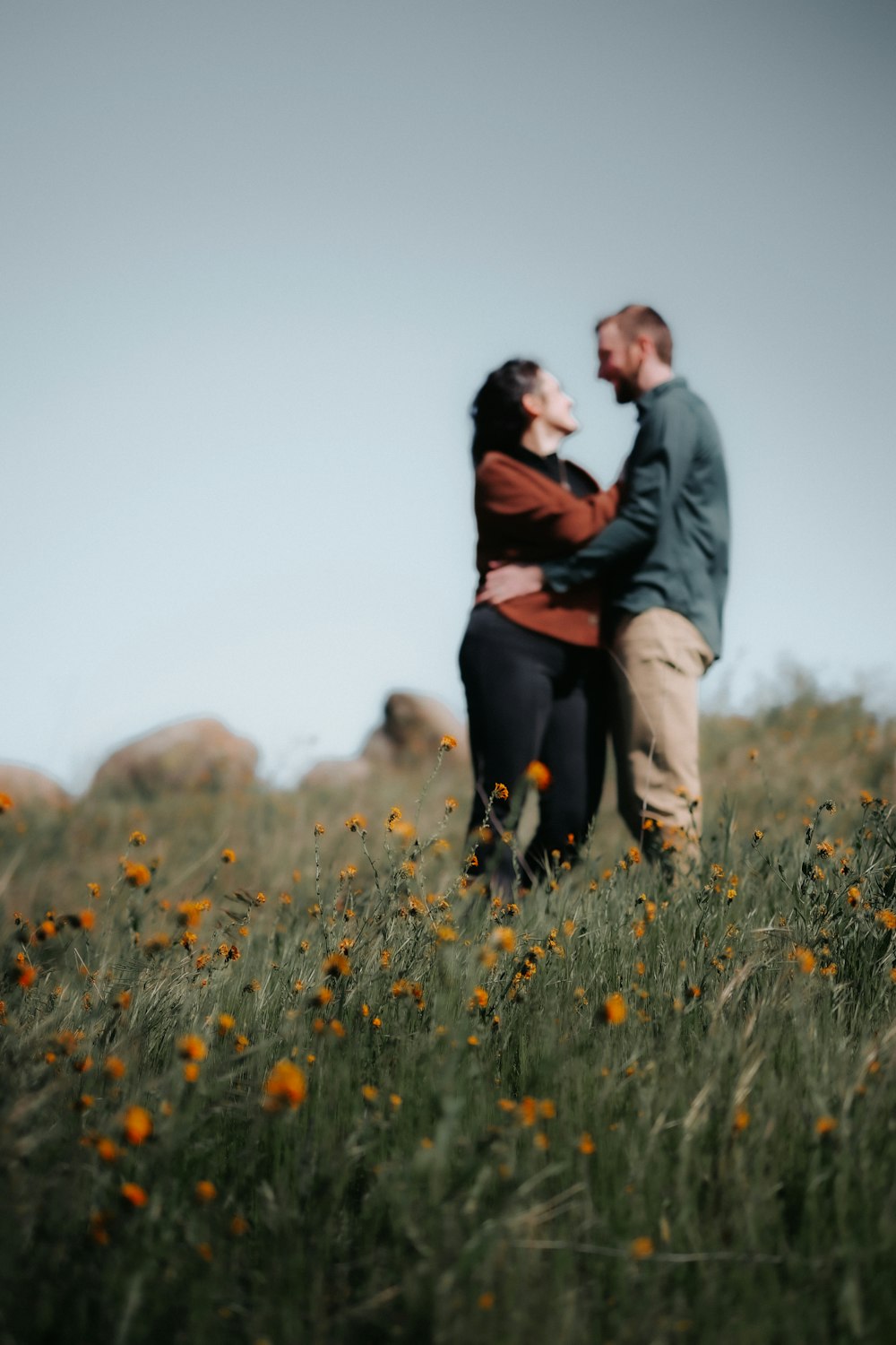 a man and woman standing in a field of flowers